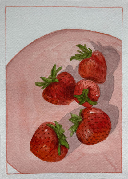 Watercolor painting of five red strawberries with green leafy tops on a soft pink oval background, set within a thin red rectangular border on textured white paper.