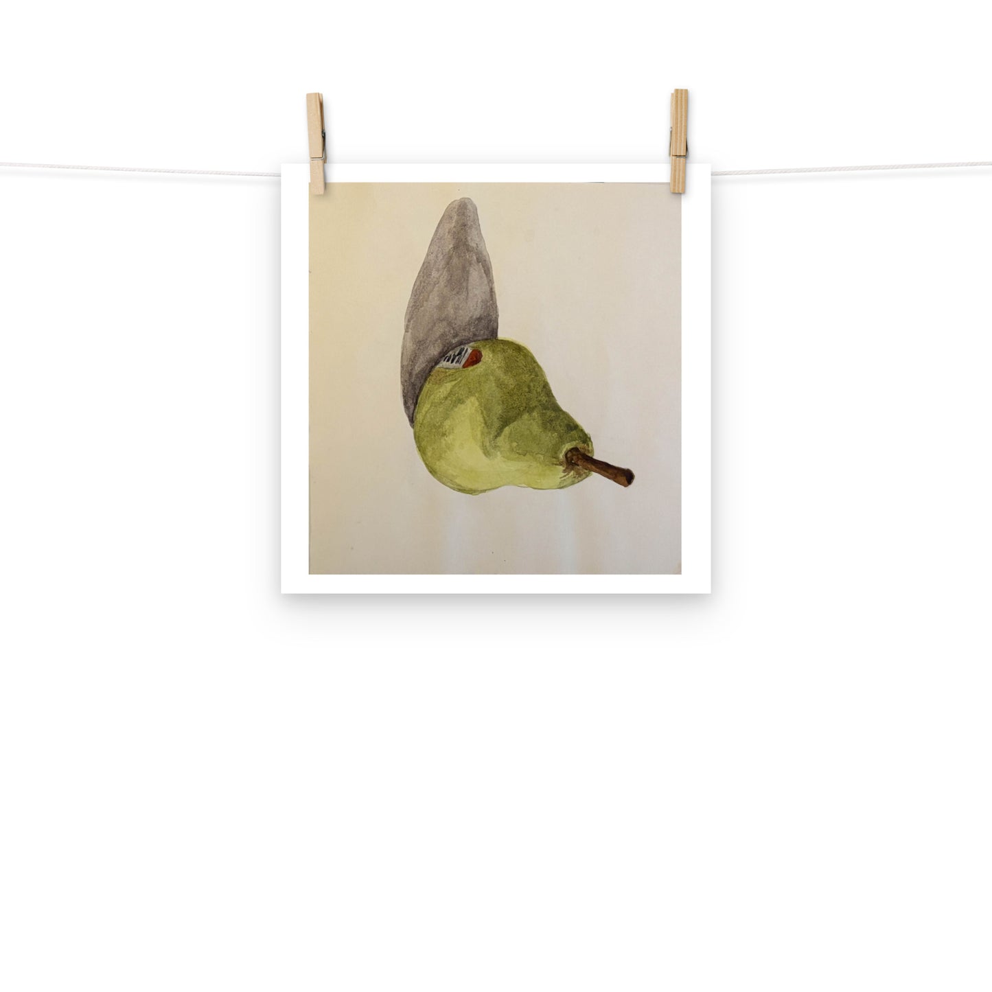 Product mockup of a watercolor print that depicts a sideways green pear against a white background 