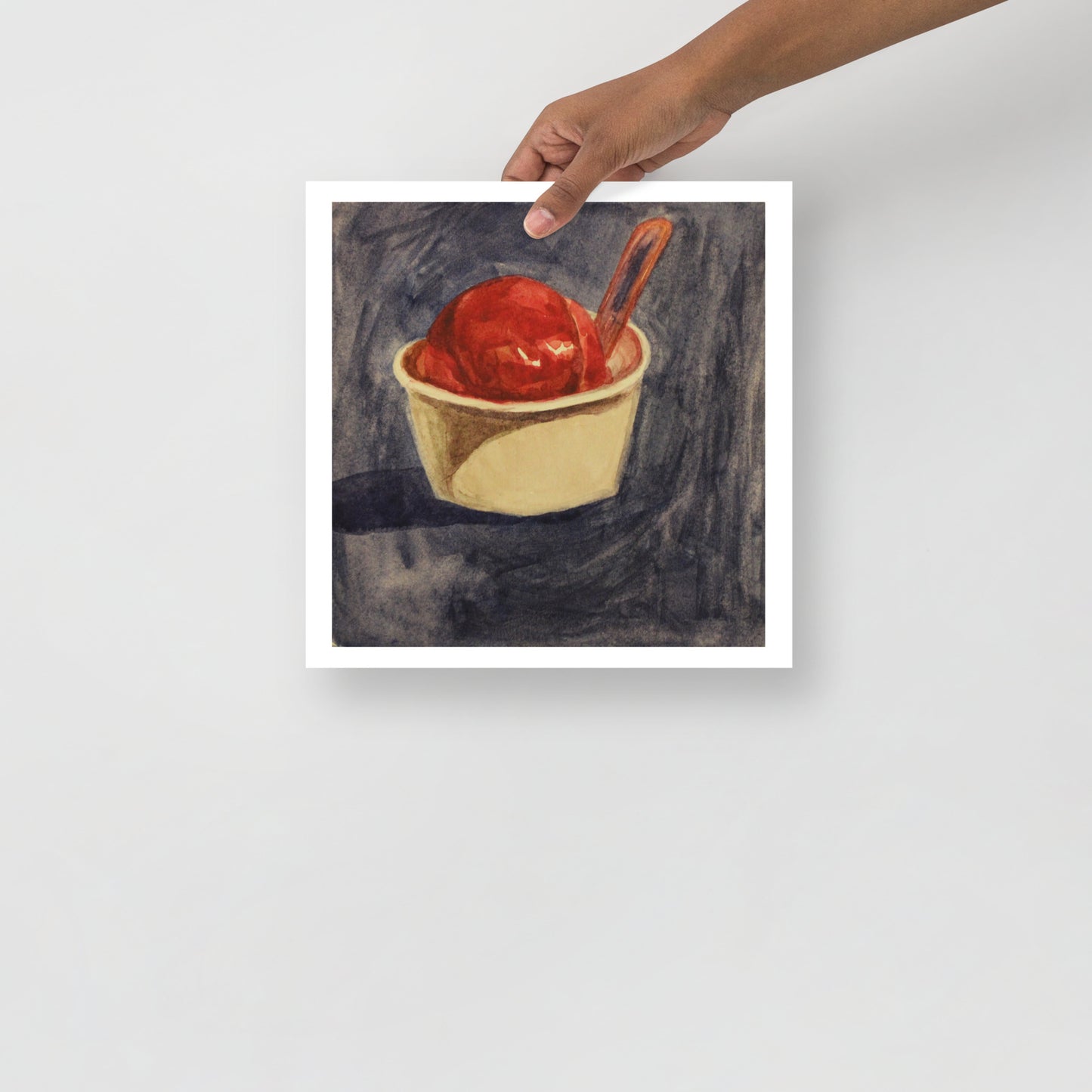 Product mockup of a watercolor print that depicts an artistic depiction of a raspberry gelato in a white cup with a spoon on a textured dark background