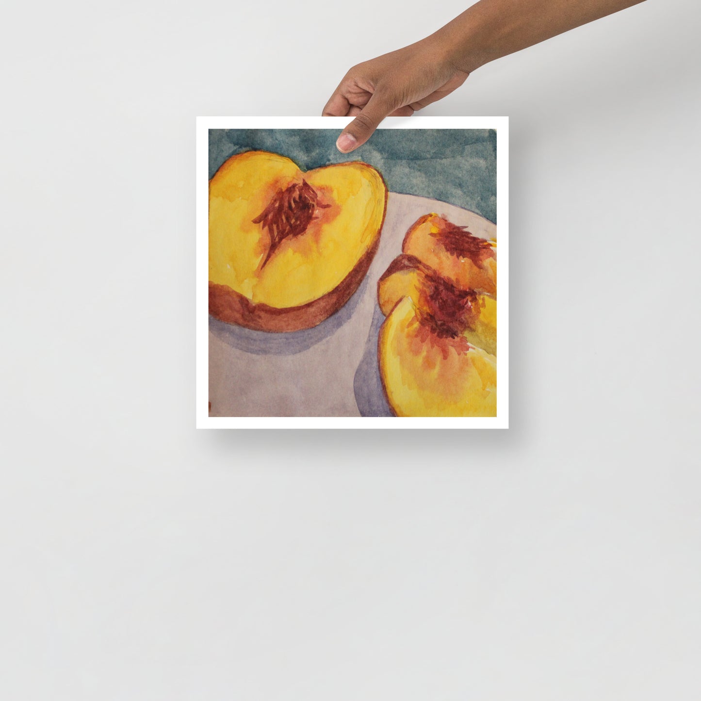 Product mockup of a watercolor print of a peach cut in half on a purple plate with a blue background