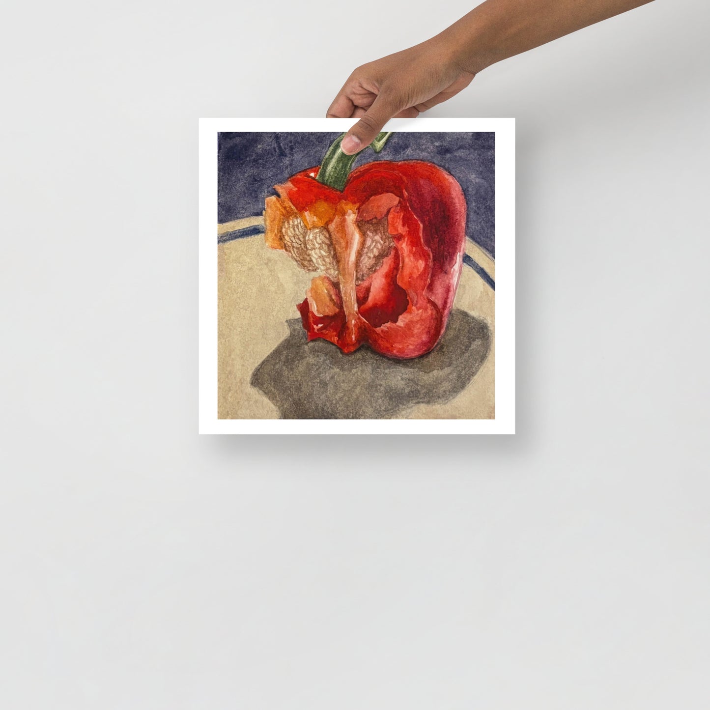 Product mockup of a watercolor painting of a red bell pepper with bites taken out of it on a textured surface with a dark background