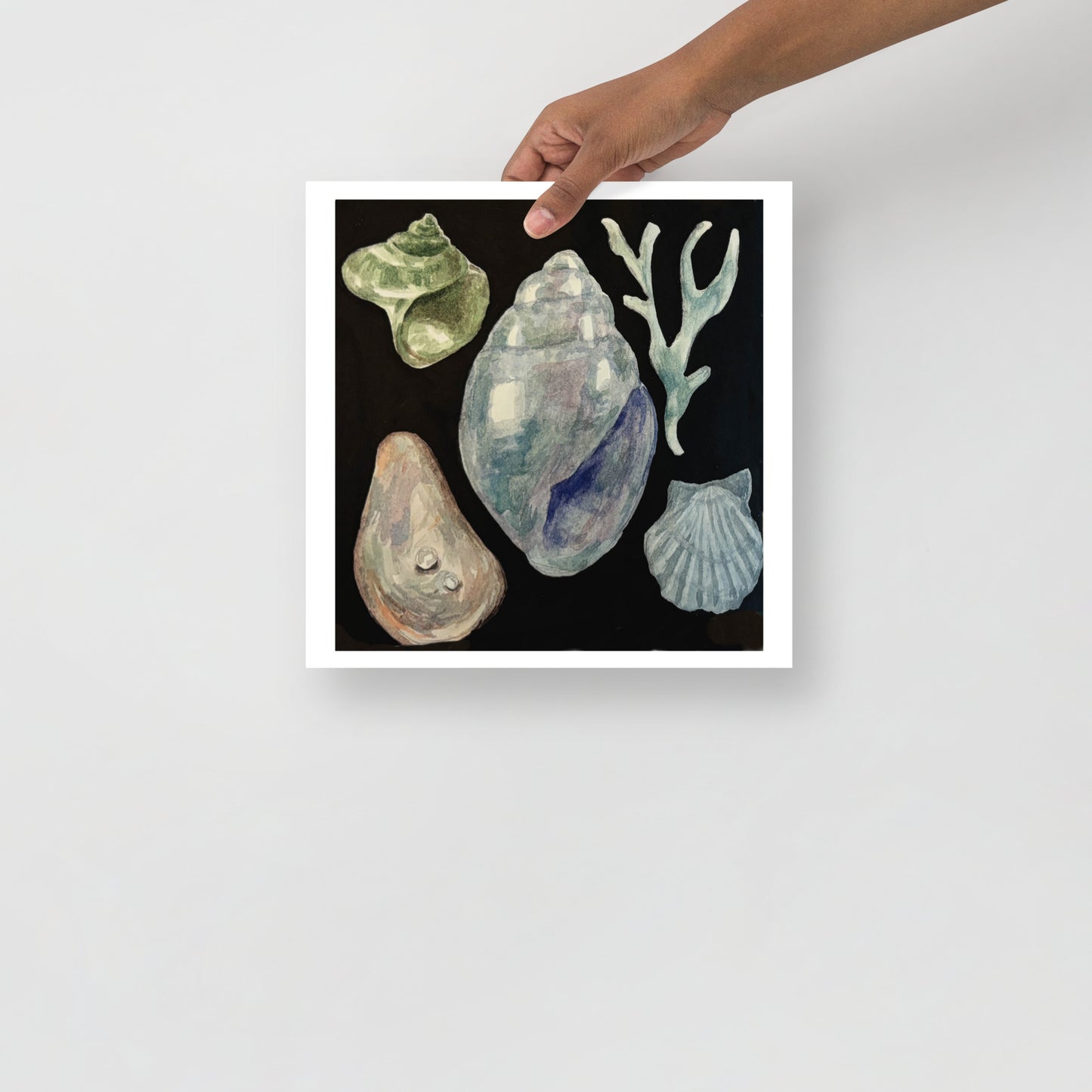 Product mockup of a watercolor painting print of various shells and seaweed on a black background