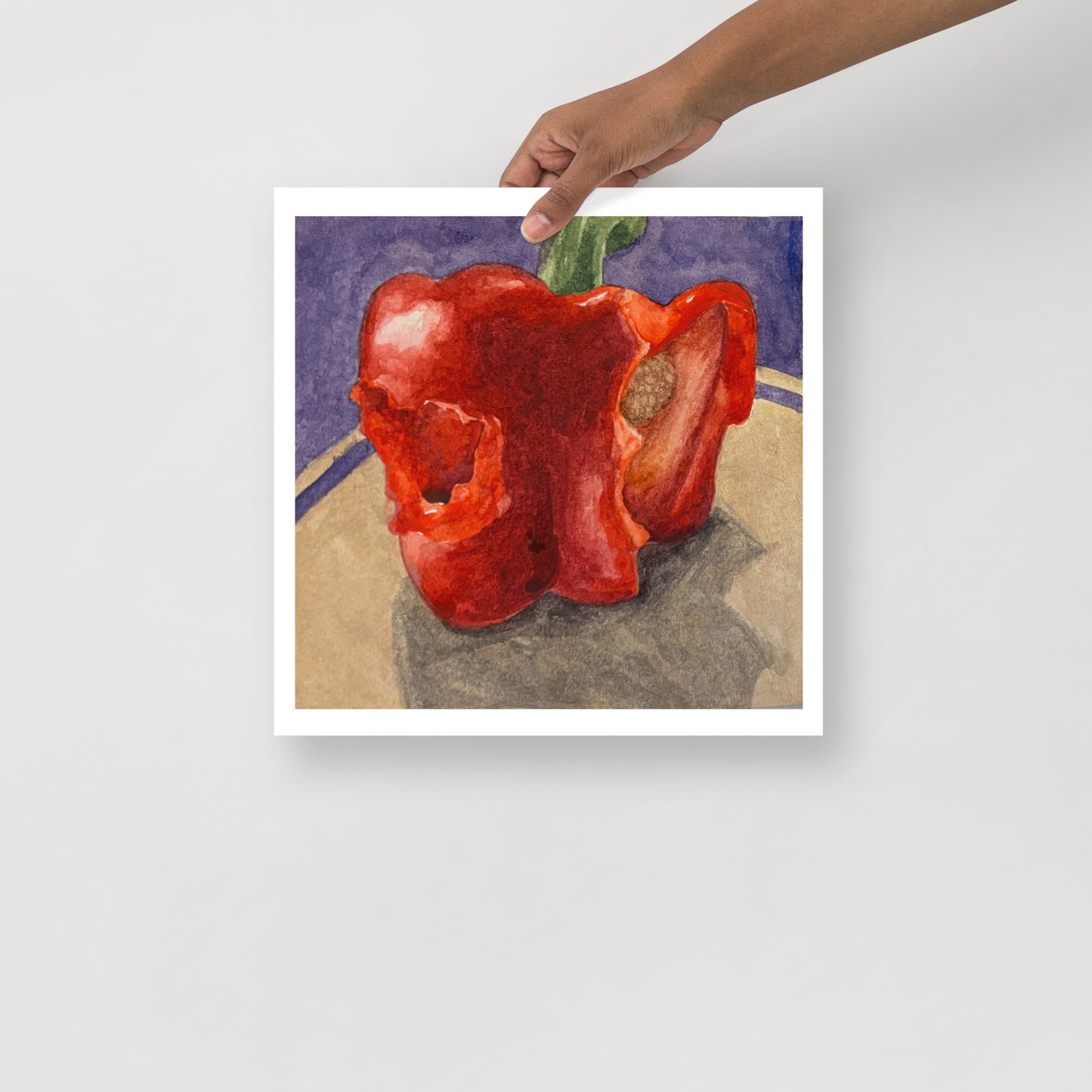 Product mockup of a watercolor painting of a red bell pepper with bites taken out of it on a textured surface with a dark background