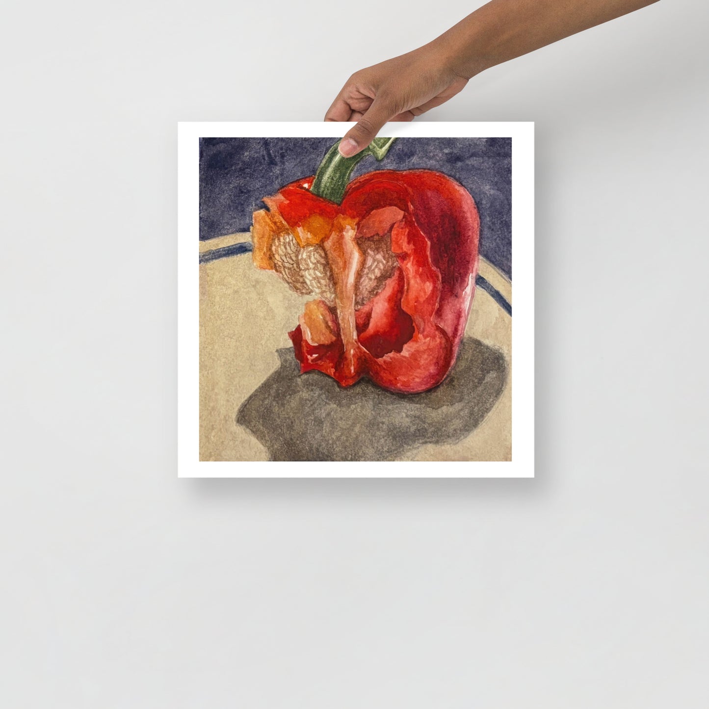 Product mockup of a watercolor painting of a red bell pepper with bites taken out of it on a textured surface with a dark background
