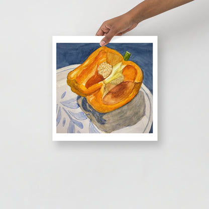 Product mockup of watercolor painting of a halved orange bell pepper on a white plate with a design against a blue background. 